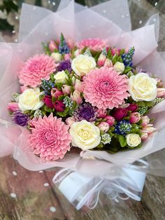 a bouquet of pink and white flowers sitting on top of a wooden table