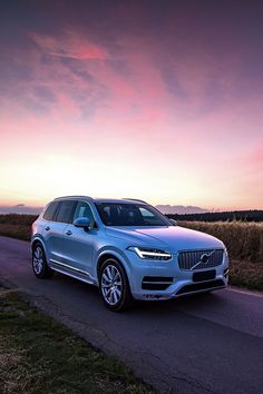 a silver volvo car parked on the side of a country road at sunset or dawn