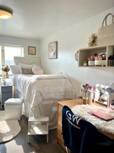 a bedroom with a bed, desk, chair and shelves on the wall next to it