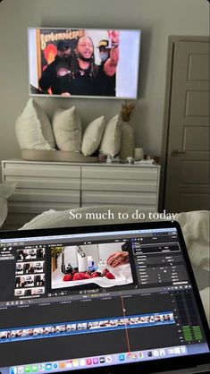 an open laptop computer sitting on top of a bed in front of a tv screen