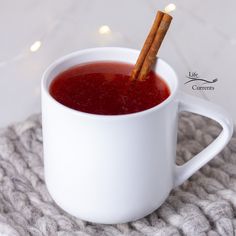 a cup filled with red liquid and cinnamon sticks sticking out of the inside of it