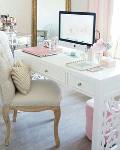 a white desk topped with a computer monitor sitting next to a chair and table covered in items