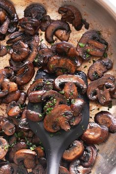 mushrooms are being cooked in a skillet with a spatula to stir them together