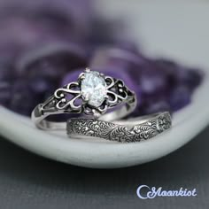 two wedding rings sitting next to each other on top of a purple and white flower