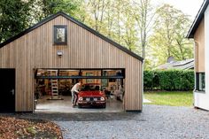 a car is parked in front of a garage with the door open and man working on it