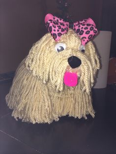 a dog made out of yarn with a pink bow on it's head and tongue sticking out