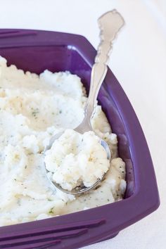 mashed potatoes and gravy in a purple dish with a spoon on the side