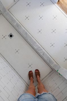 a person standing on a tiled floor with their feet up in the air next to a shower