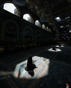 a person sitting on the floor in an ornate room with many windows and rugs