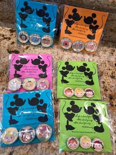 four mickey mouse magnets in plastic bags on a counter top with some other magnets next to them