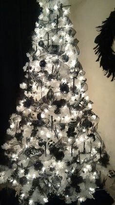 a white christmas tree decorated with black and silver ornaments