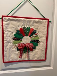 a christmas wreath hanging on a door with ribbon around the front and back part of it