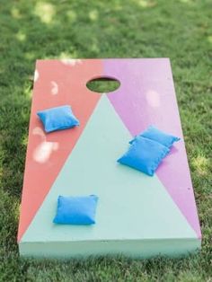 a cornhole game set up on the grass with blue pillows sitting on it's side