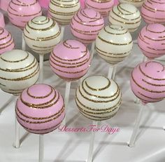 there are many pink and white cake pops on the stick with gold glitters in them