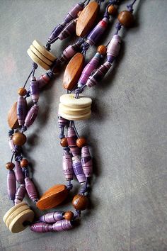 a necklace made out of beads and wooden buttons on a table with a gray surface