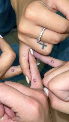 four people holding hands with tattoos on their fingers and one has a cross tattooed on it