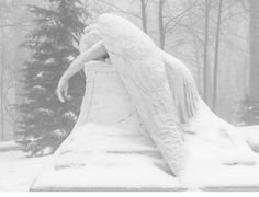 an angel statue sitting on top of a snow covered ground