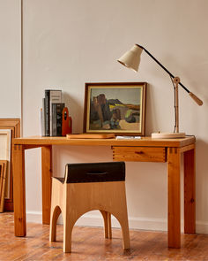 a wooden desk with a lamp and pictures on it