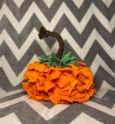 an orange pumpkin sitting on top of a gray and white blanket