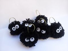 four black pom - poms with googly eyes hanging from hooks