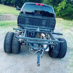 the back end of a black truck with four wheels on it's flatbed