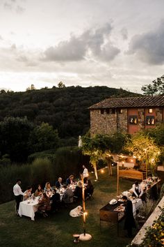 a group of people sitting around a table in the middle of a lush green field