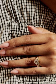 a woman's hand with a ring on her left wrist, wearing a checkered shirt