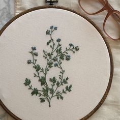 a close up of a embroidery on a table with some glasses and a pair of eyeglasses