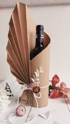 a wine bottle in a brown paper bag with flowers around it and a white ribbon