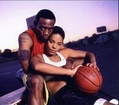 a man and woman sitting next to each other holding a basketball