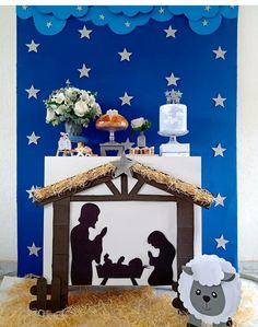 a nativity scene with sheep, lamb and mangerau on display in front of a blue backdrop