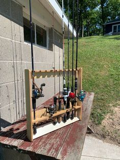 fishing rods and reels are hanging on a wooden shelf outside the building with grass in the background