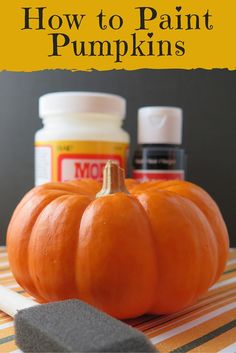 an orange pumpkin sitting on top of a table next to some paint and a sponge