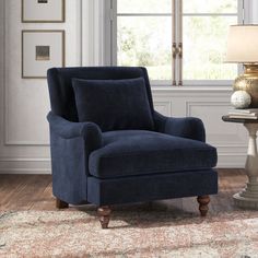 a blue chair sitting on top of a wooden floor next to a lamp and window