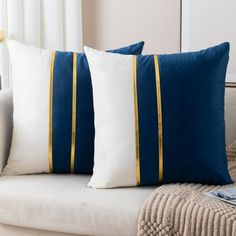 two blue and white pillows sitting on top of a couch