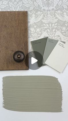 some paint swatches are sitting on a table next to a wooden frame and wallpaper