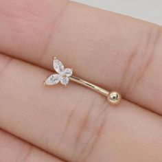 a tiny gold nose ring with a flower on the top and two small white flowers on the bottom