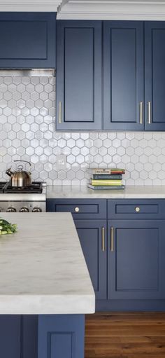 a kitchen with blue cabinets and marble counter tops