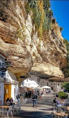 people are sitting at tables under the cliff