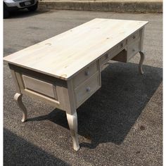 a white desk with drawers sitting on the ground in front of a car parked next to it