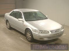 a silver car is parked in a parking lot next to a garage with a door open