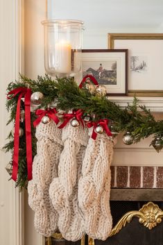 christmas stockings hanging from a mantel decorated with greenery