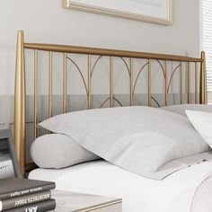 a bed with white pillows and gold headboard