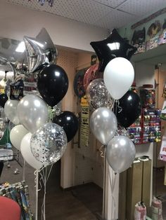 black and white balloons are hanging from the ceiling in a room filled with other items