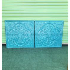 two large blue tiles sitting next to each other in front of a green wall with a yellow door