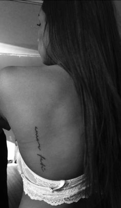 the back of a woman's left shoulder with words written on her right side