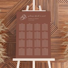 a brown and white wedding seating chart on an easel with pamy grass in the background