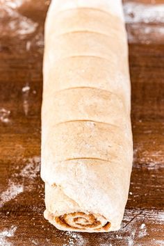 a long loaf of bread sitting on top of a wooden table