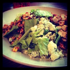 a white plate topped with lettuce, chicken and other food on top of it