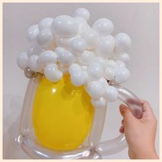 a person holding a yellow vase with white balloons in it